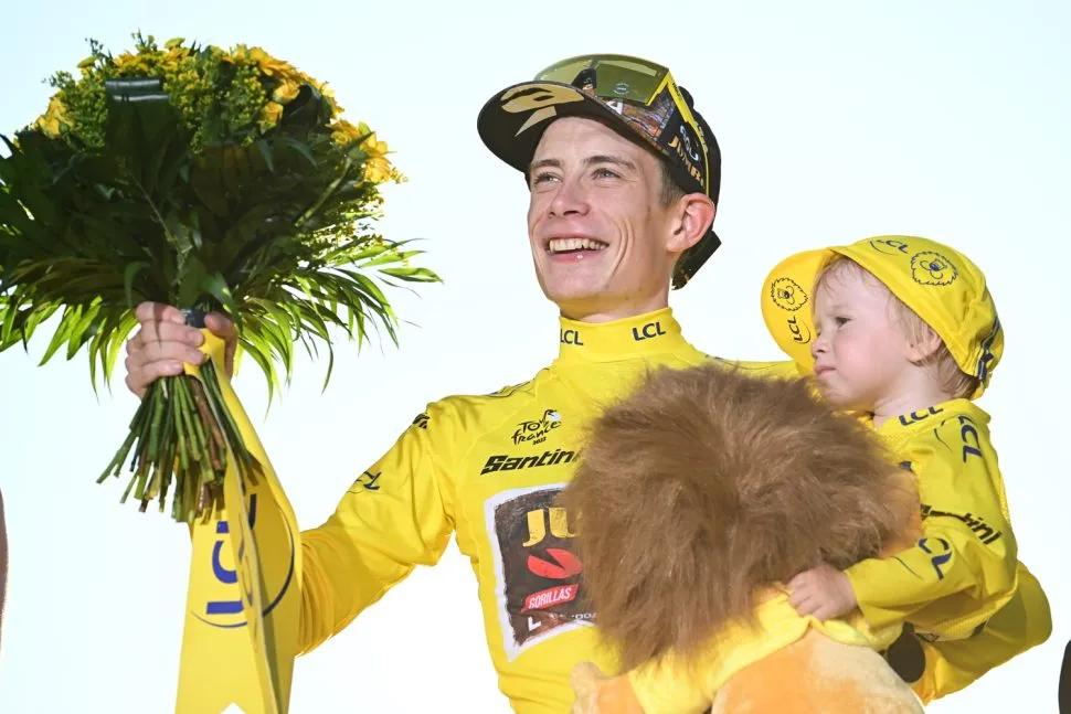 cyclist on podium in yellow holding child also in yellow and bouquet of flowers