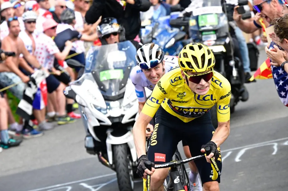 cyclists in white and yellow grimace as they race up hill